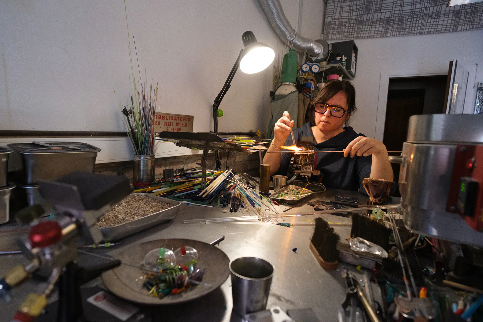 An artisan at the lamp in her Murano workshop, shot with an ultra wide lens
