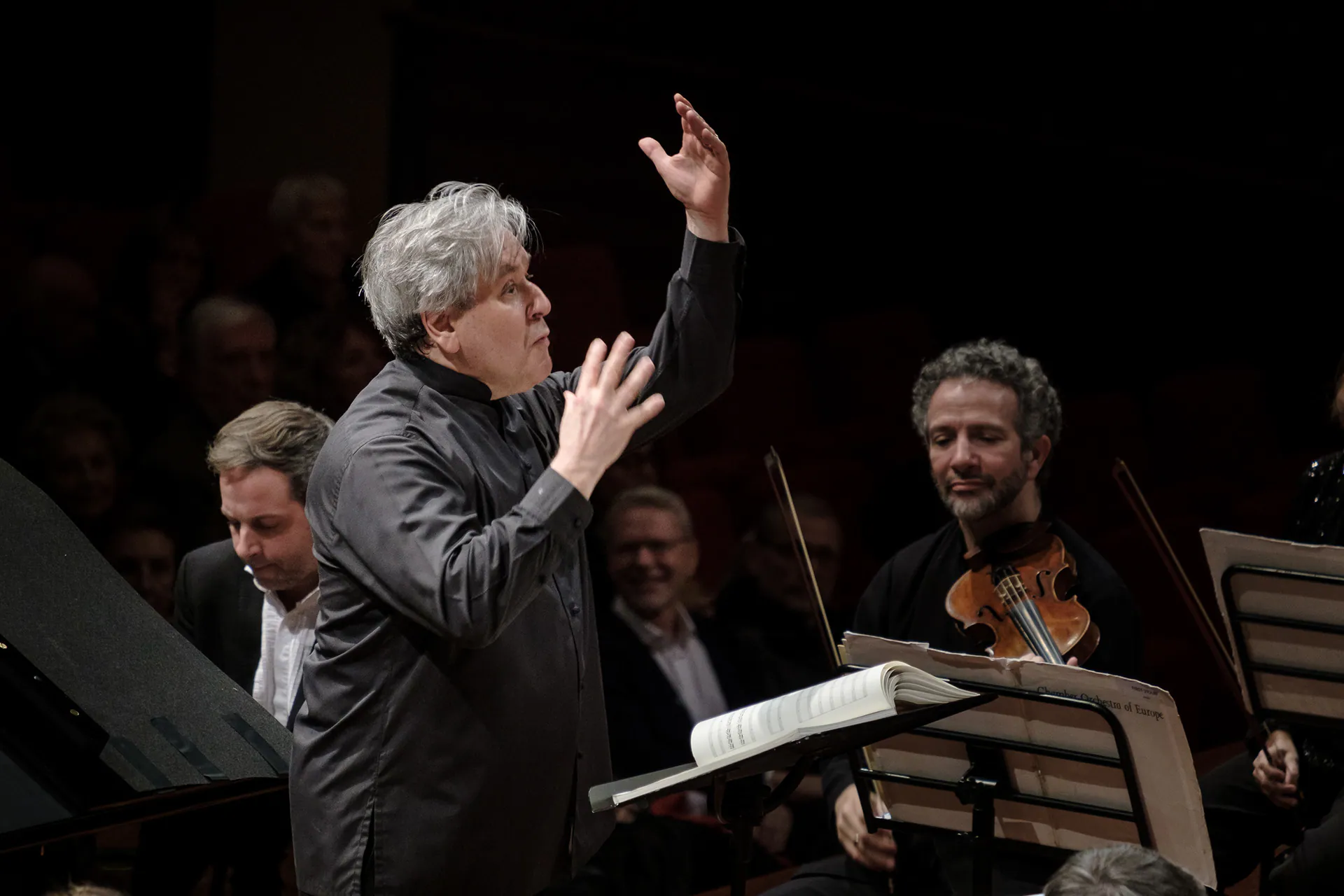 Sir Antonio Pappano dirige con il braccio alzato, davanti ai musicisti della Chamber Orchestra of Europe.