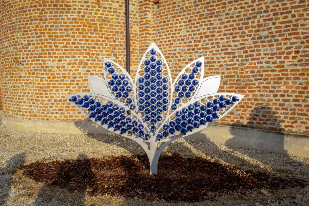 Un fiore di ceramica blu e bianca installato contro un muro di mattoni