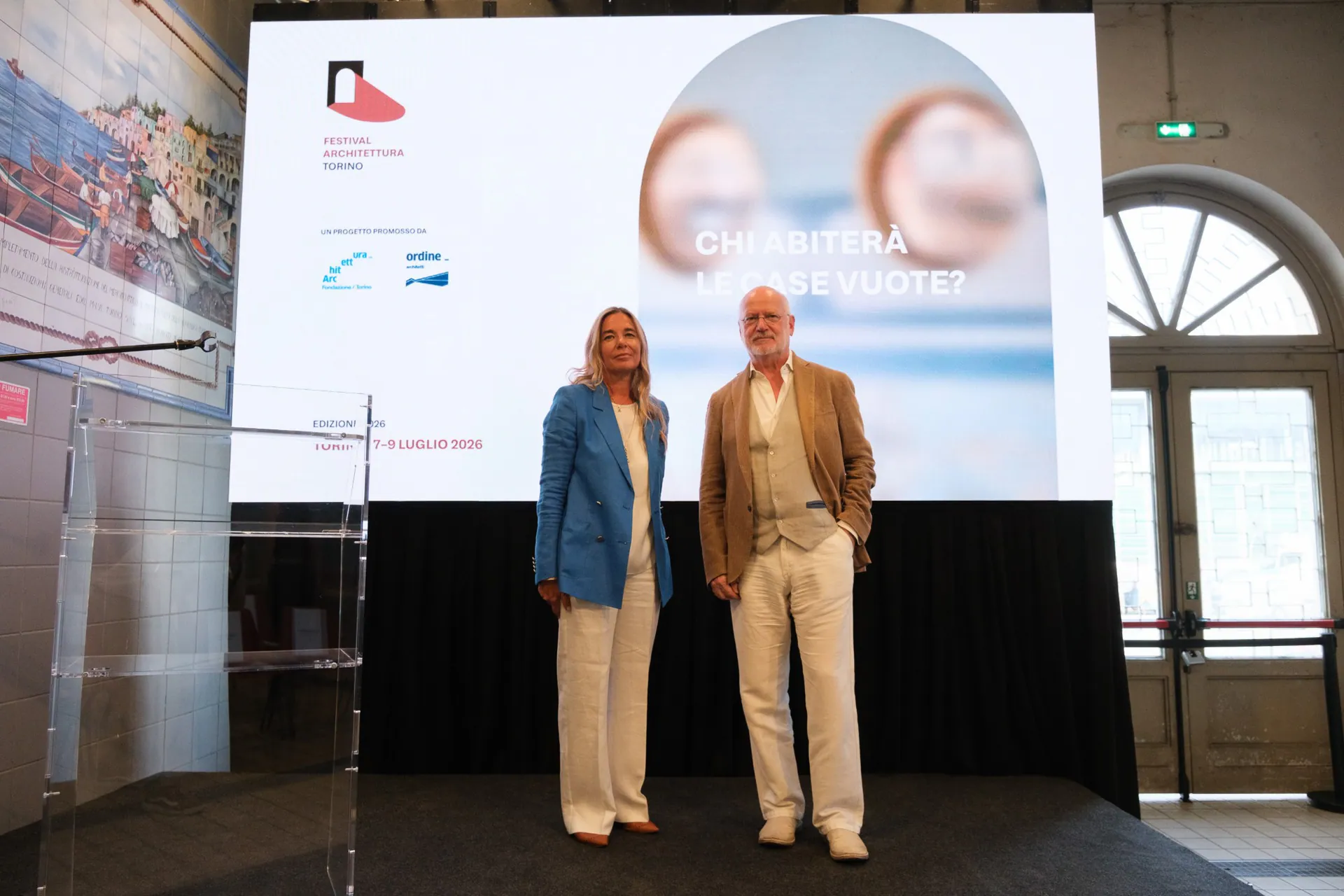 Alessandra Siviero with a festival guest on stage, in front of the 2026 edition artwork