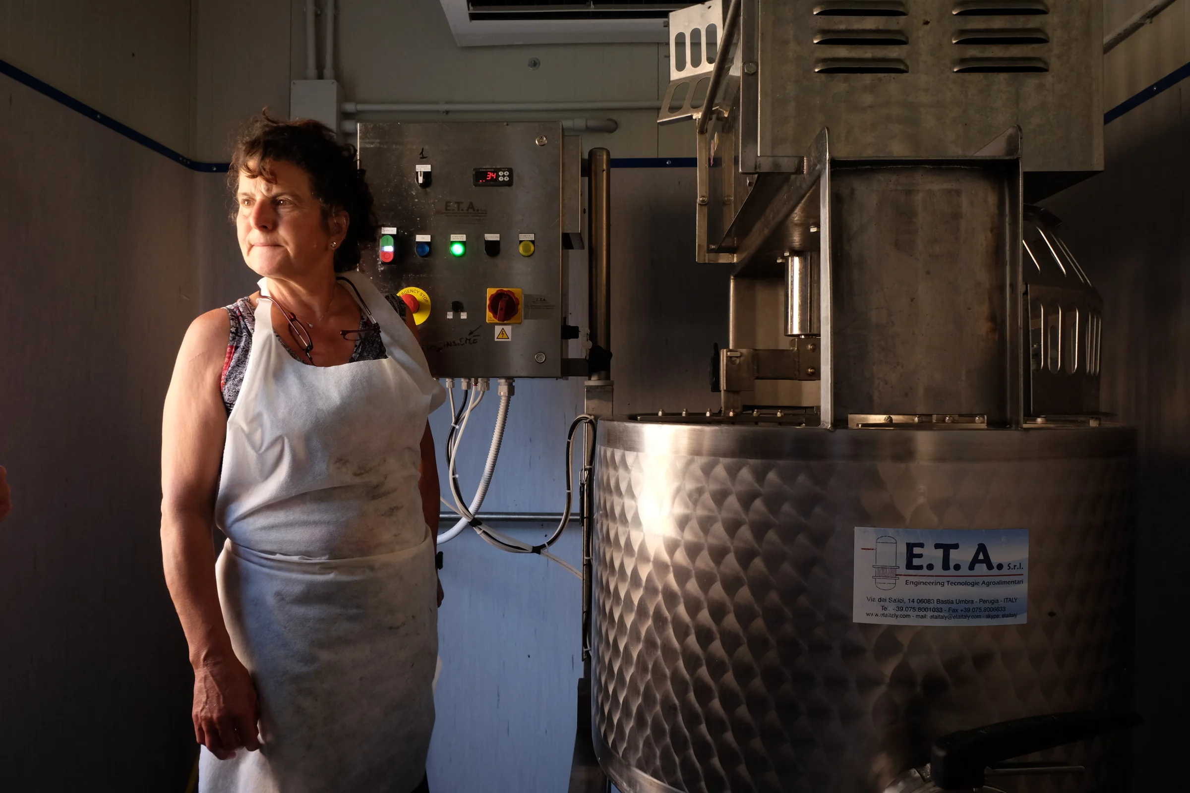 A cheesemaker in an apron next to the milk vat in the dairy