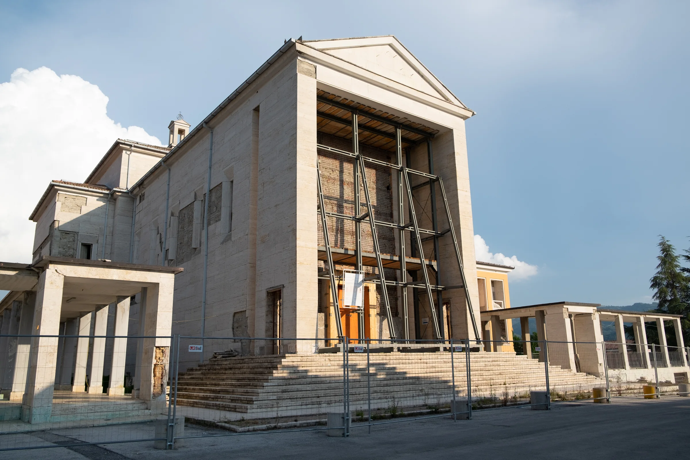 The church of the Don Minozzi religious centre with its façade held by a steel frame, behind barriers