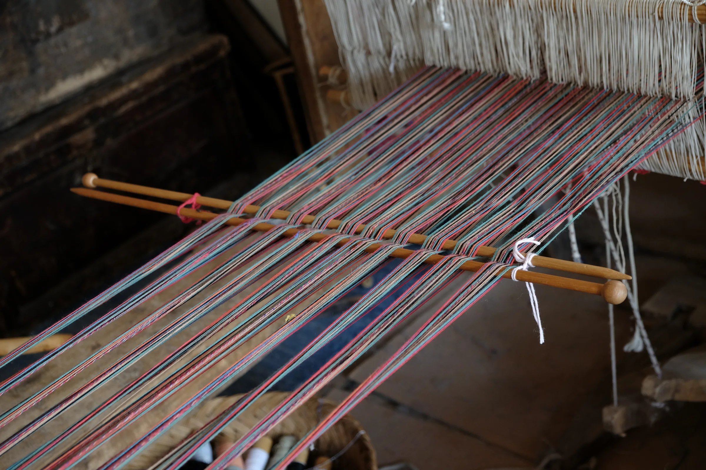 Red, blue and green threads separated by two wooden rods