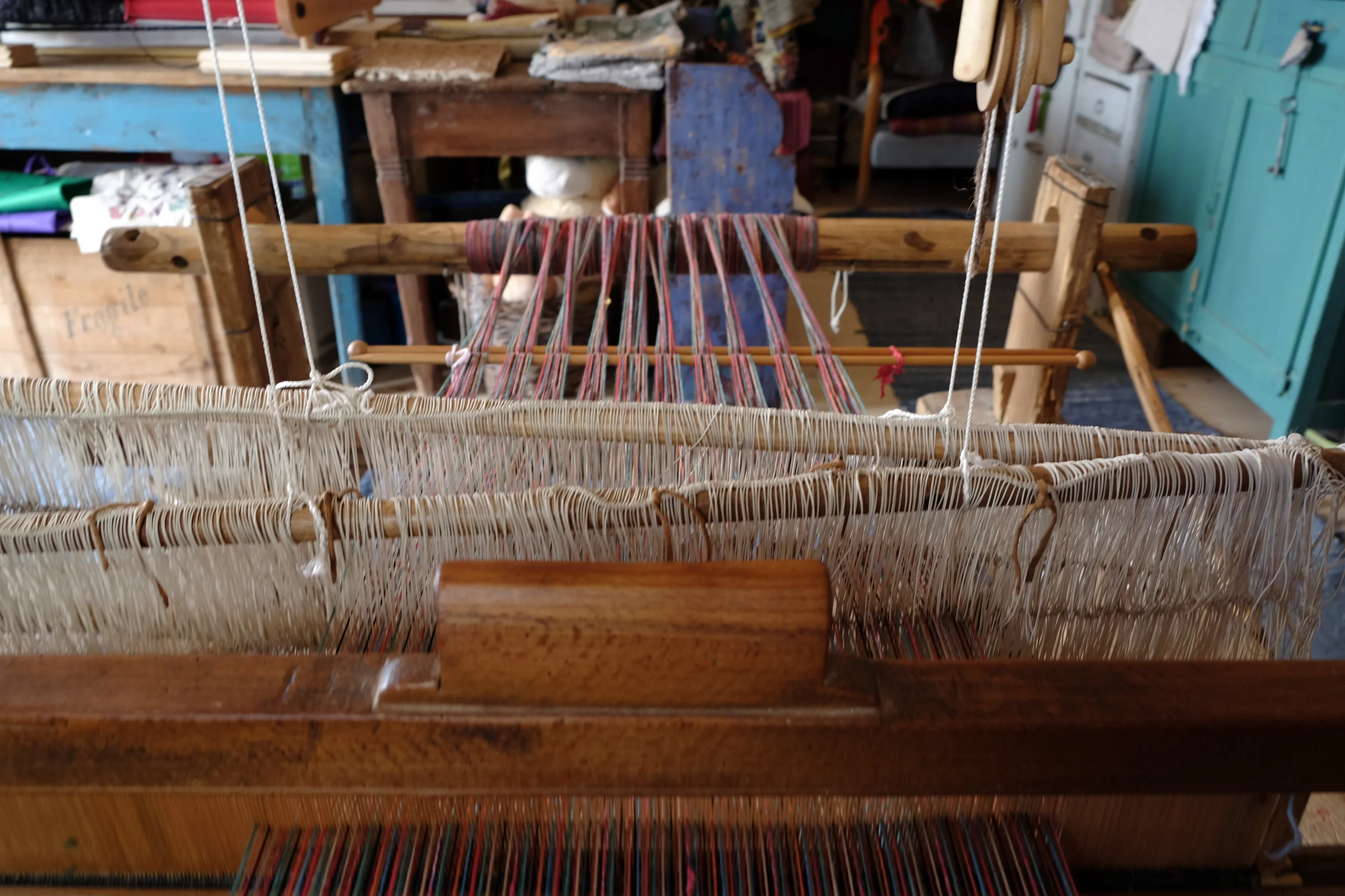 The loom’s reed and the white warp threads, seen from the weaver’s seat