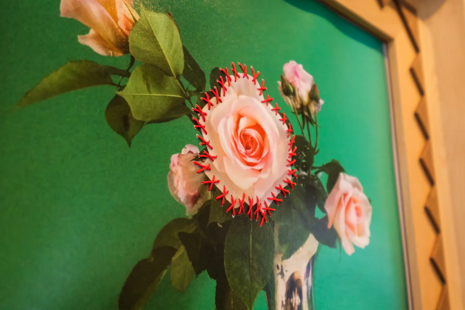 Una rosa in fotografia cucita con punti rossi su fondo verde