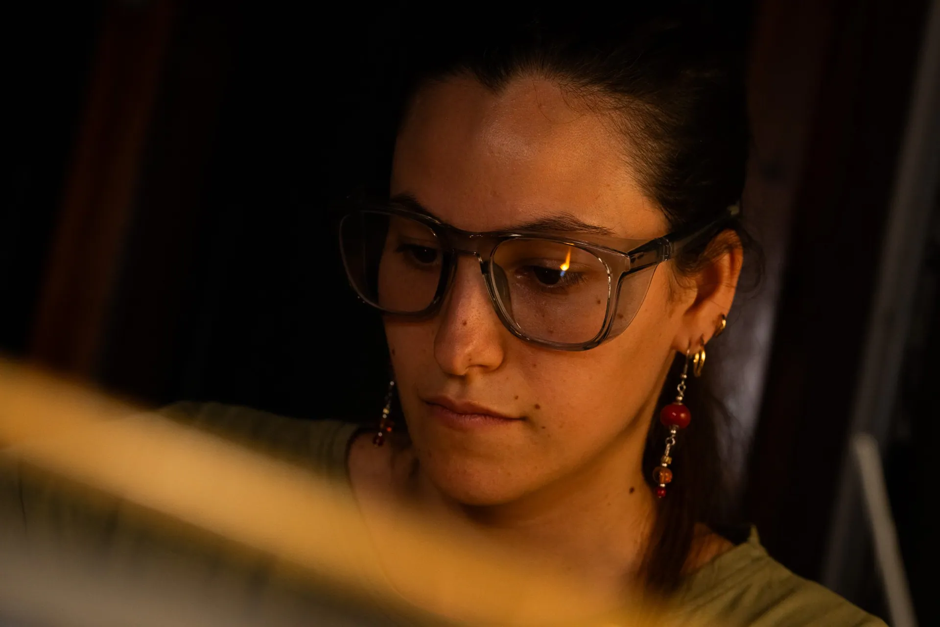 Portrait of a young artisan, with the flame reflected in her glasses