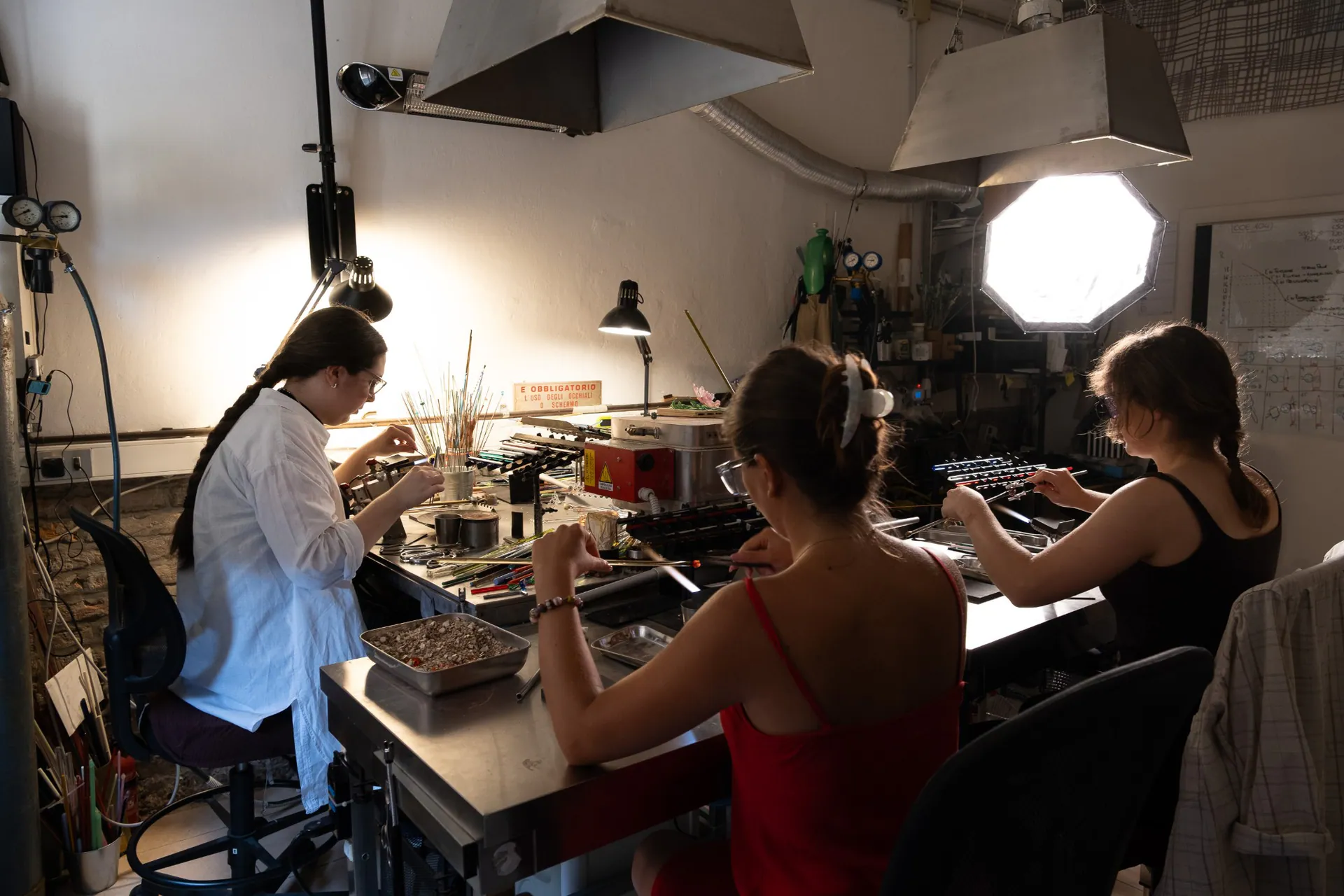Three young artisans at work in the lampworked bead workshop