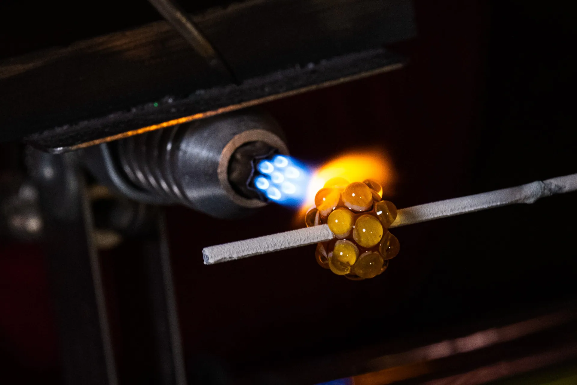 A yellow glass bead taking shape in the torch flame