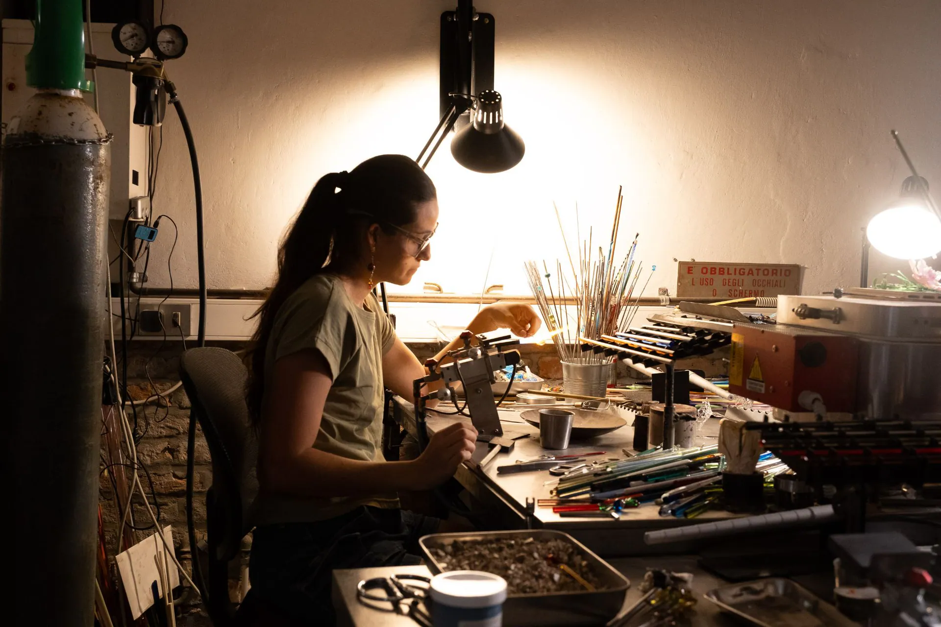 A young artisan at her bench under the lamp light