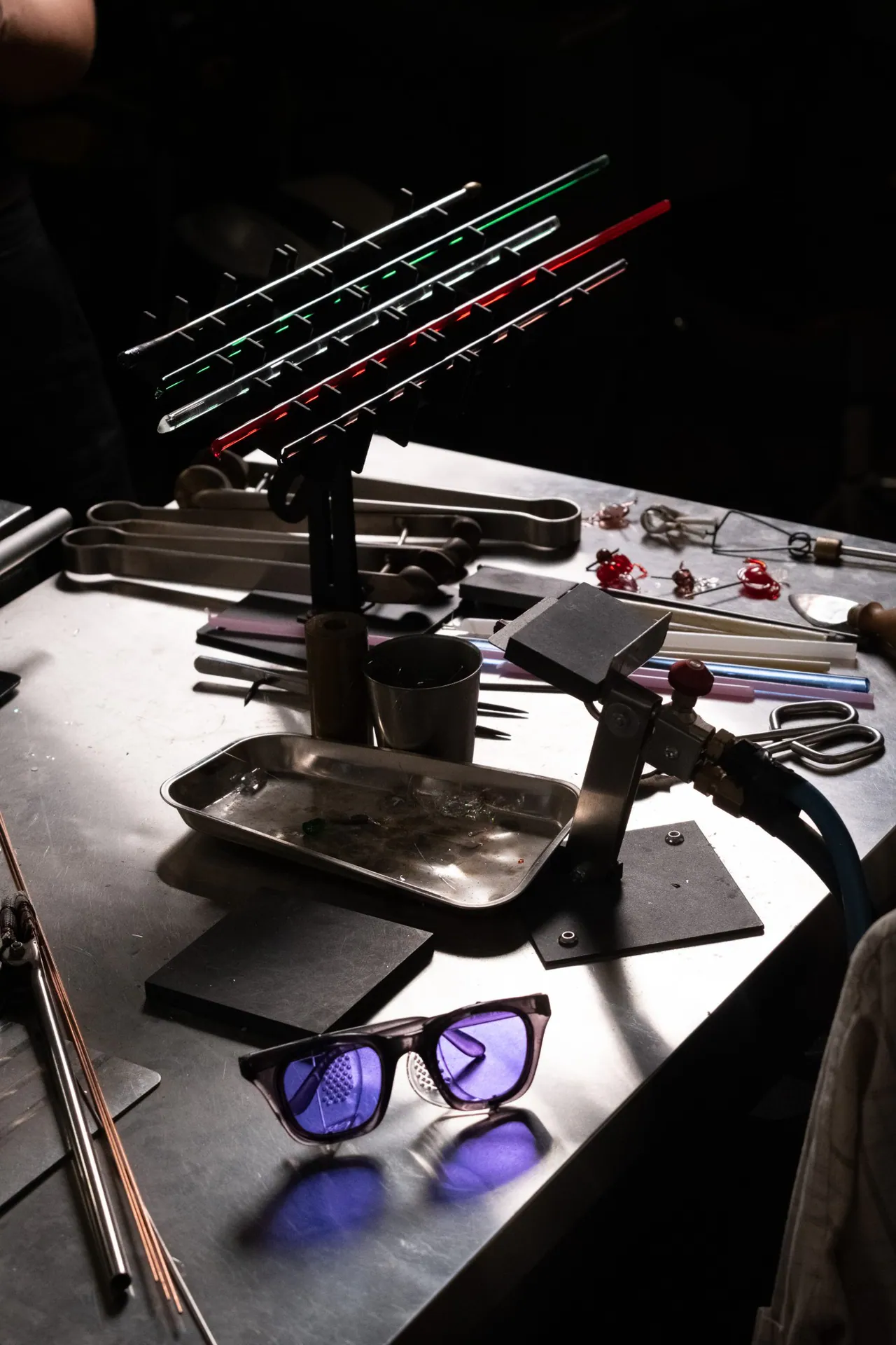The workbench with glass rods, pliers and protective glasses
