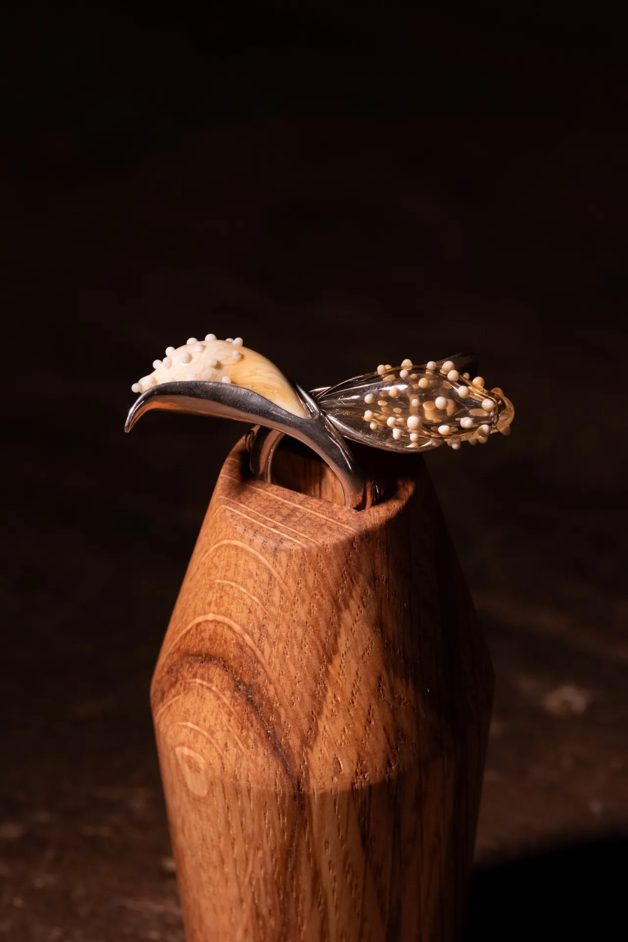A ring with glass beads made by a scholarship recipient, on a wooden stand