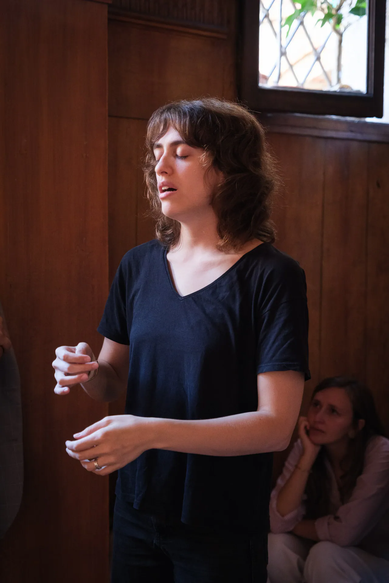 Nina Baietta sings during the performance, in a wood-panelled room.
