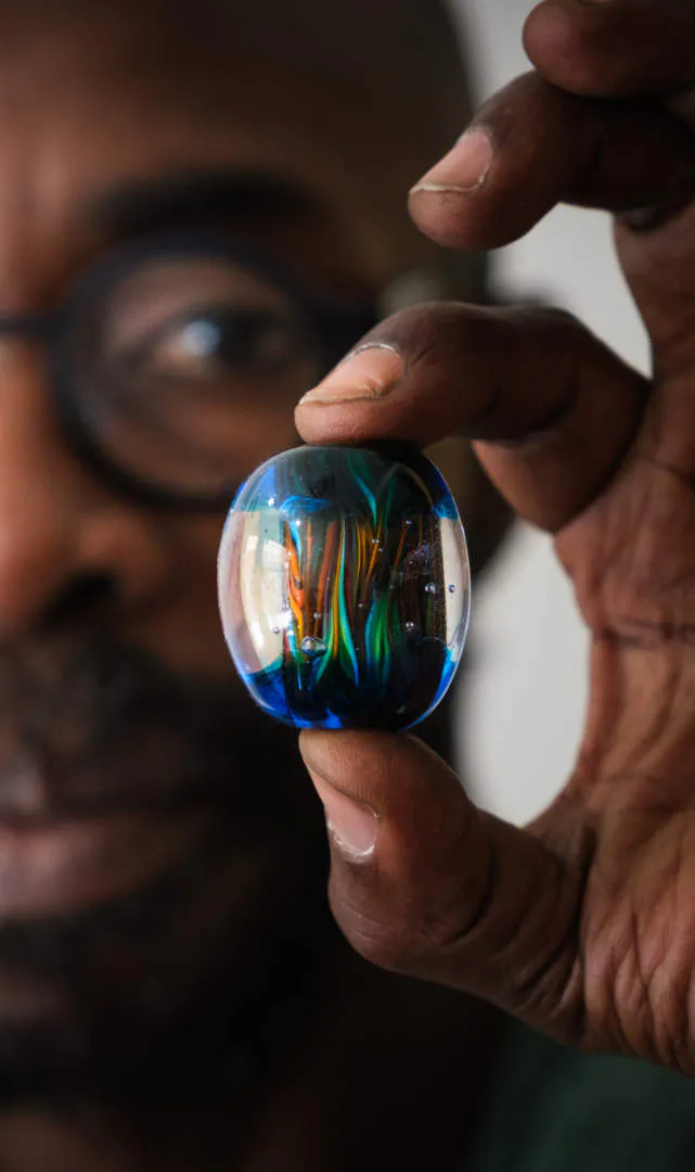 Moulaye mostra una sua perla di vetro blu e verde