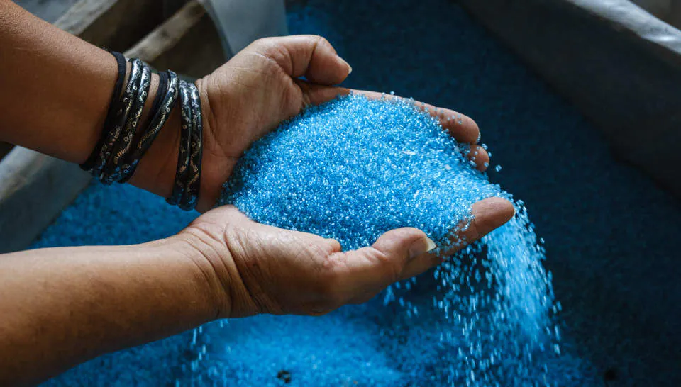 Mani che raccolgono perline di vetro azzurre