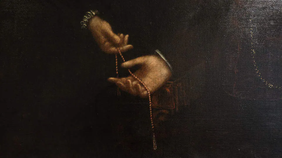 Dettaglio di un dipinto antico con mani che infilano perle