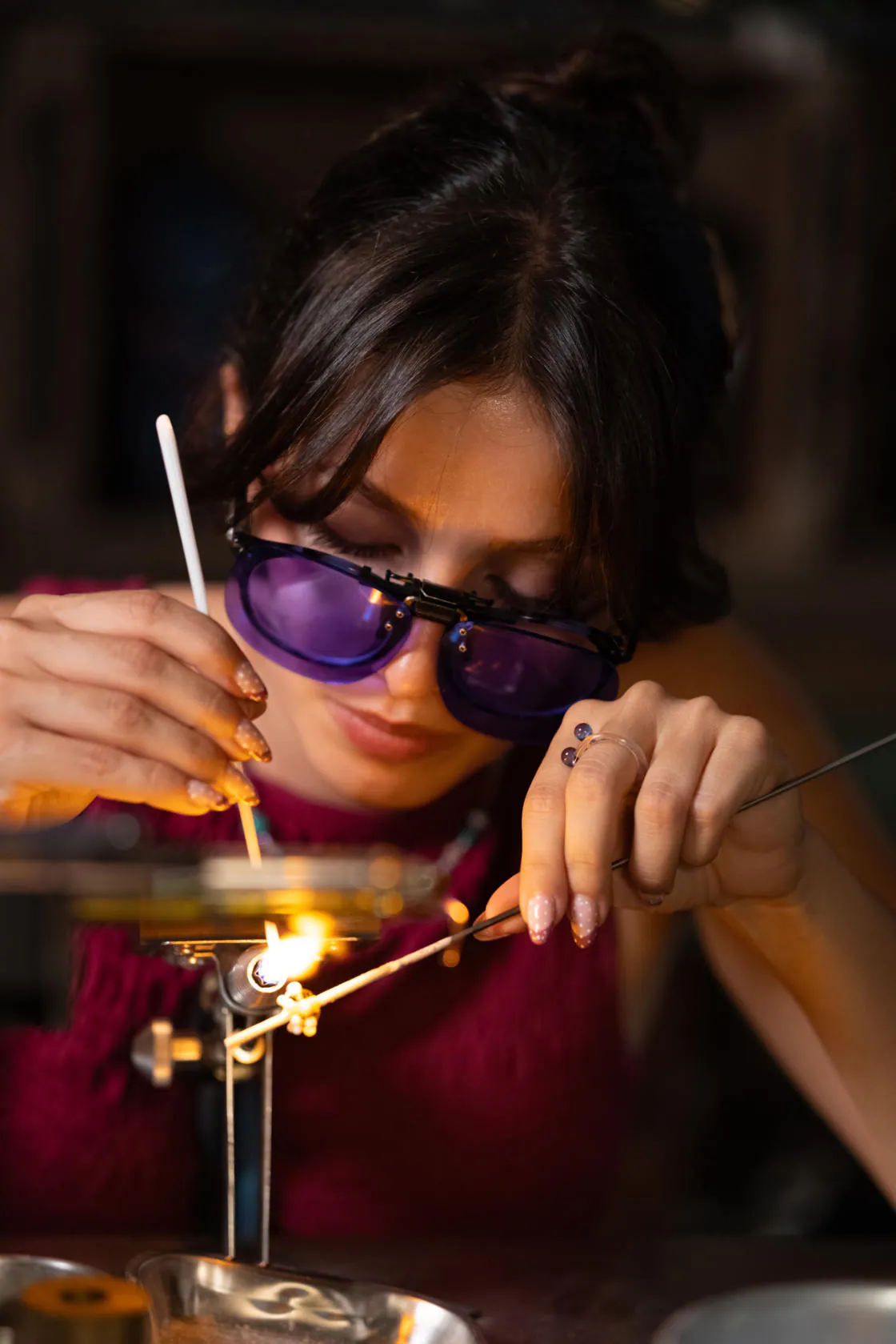 Una giovane artigiana con occhiali viola che lavora una perla