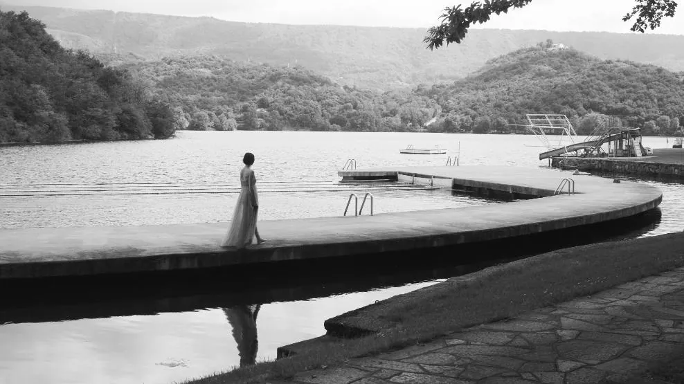 Fotogramma: la protagonista su un pontile in riva al lago