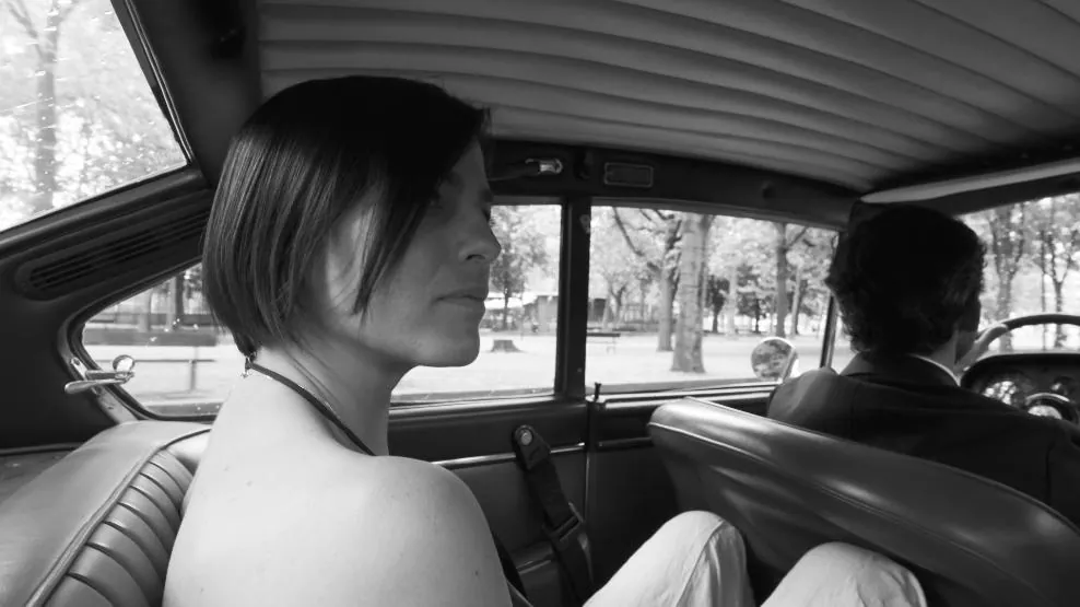 Fotogramma: la protagonista seduta sul sedile posteriore di un’auto