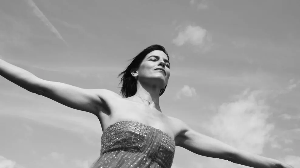Fotogramma: la protagonista con le braccia aperte contro il cielo