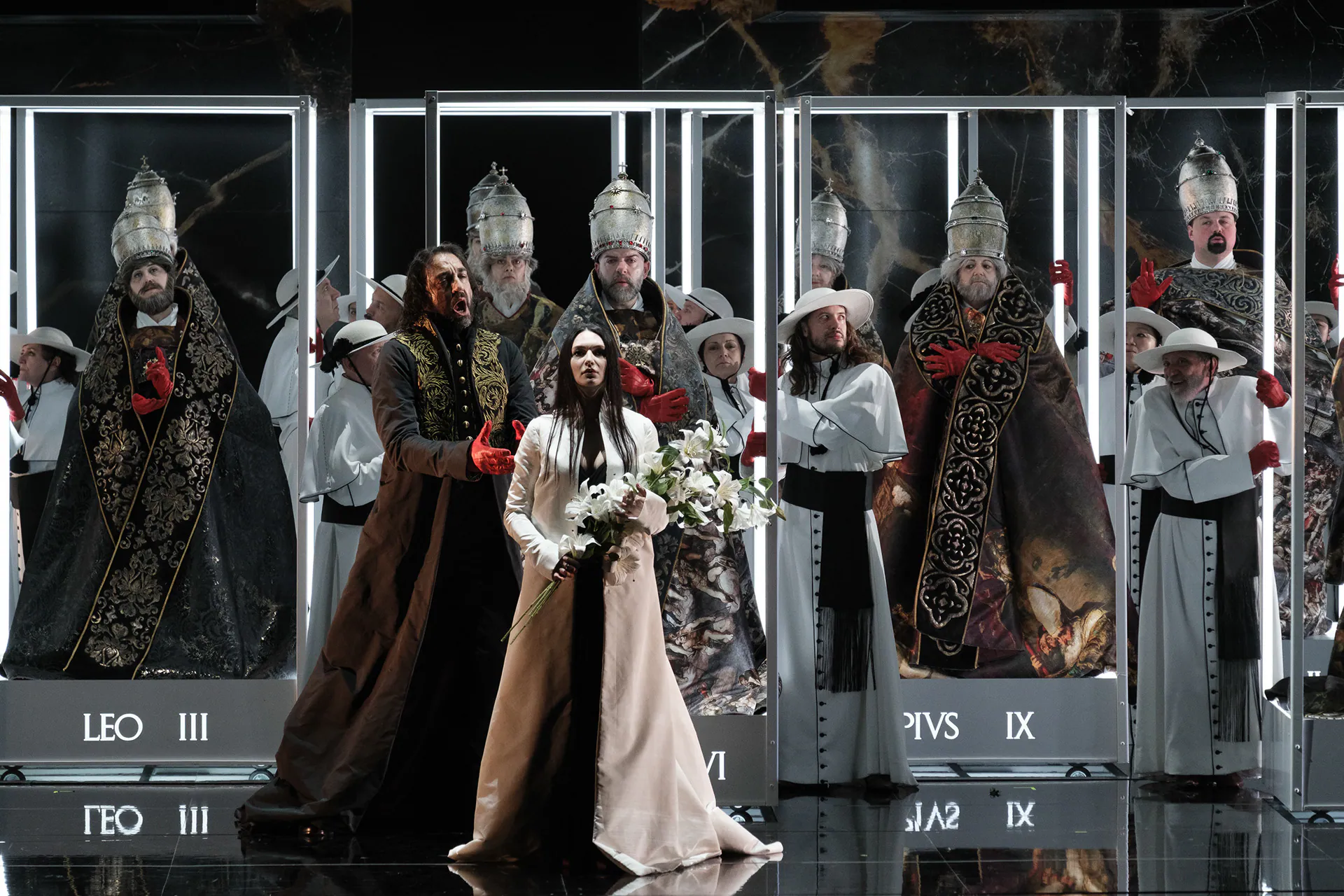 The chorus dressed as popes and cardinals inside illuminated glass cases, in Stefano Poda’s staging of Tosca.